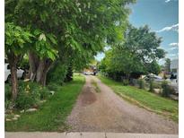 Long gravel driveway lined with mature trees and lush landscaping leading to a home at 5870 Nelson Ct, Arvada, CO 80004