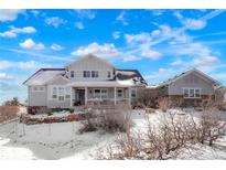 Charming two-story home with covered porch, snow-covered yard, and blue skies at 7186 Weaver Cir, Castle Rock, CO 80104