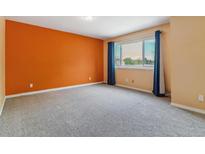 A bright bedroom with gray carpet, peach walls, and window with blue curtains at 1160 S Clinton St # 40, Denver, CO 80247