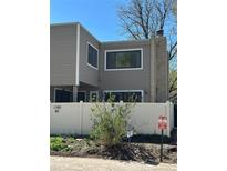 Two-story home with neutral siding, white fence, and stone chimney detail at 1160 S Clinton St # 40, Denver, CO 80247