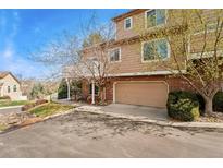 Two-story home with a brick base, tan upper level, attached garage, and front balcony at 6819 S Webster St # E, Littleton, CO 80128