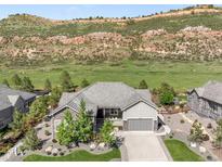 Charming single-Gathering home with stone accents and lush landscaping against a mountain backdrop at 4868 Hogback Ridge Rd, Morrison, CO 80465
