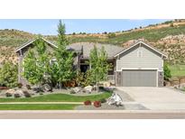 Beautiful single Gathering home boasts stone and siding details, landscaped front yard, and attached garage at 4868 Hogback Ridge Rd, Morrison, CO 80465