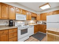 Traditional kitchen featuring wooden cabinets, white appliances, and a laminate countertop at 635 S Alton Way # 3B, Denver, CO 80247