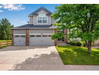 Charming two-story home with a three-car garage, manicured lawn, and mature landscaping at 11830 Snowshoe Dr, Parker, CO 80138