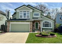 Charming two-story home featuring a stone facade, green siding, well-maintained lawn, and attached two-car garage at 5432 S Cathay Way, Centennial, CO 80015