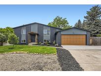 Split level home with black brick and siding, a well manicured lawn, and a two car garage at 7325 Taft Ct, Arvada, CO 80005