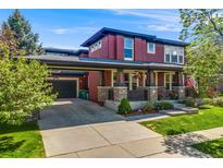 Charming two-story home featuring a covered porch, attached garage, and well-maintained landscaping at 13324 W 86Th Dr, Arvada, CO 80005