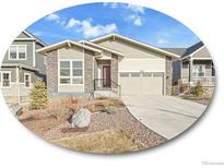 Charming single-Gathering home featuring a well-maintained lawn, a two-car garage, and stone detailing at 8894 River Peak Cir, Littleton, CO 80125