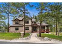Charming two-story home with a stone accent, a covered porch, and professional landscaping at 7737 Taylor Cir, Larkspur, CO 80118