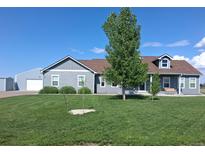 Charming single-story home with a large, lush front yard and a detached garage at 177 W 8Th Ave, Byers, CO 80103