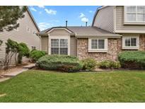 Charming townhome featuring a well-maintained lawn and stone facade, creating a welcoming curb appeal at 1276 S Zeno Cir # A, Aurora, CO 80017