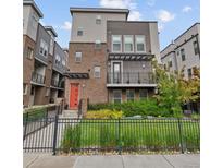 Stylish modern townhouse with a brick facade, balcony, a red front door and a well-maintained fenced yard at 1325 Jackson St, Denver, CO 80206