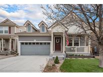 Charming two-story home with a covered front porch, grey siding, a well-kept lawn and an attached garage at 1811 Hogan Ct, Castle Rock, CO 80109