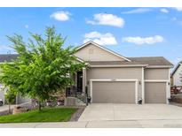 Charming two-story home with a well-manicured front lawn, three-car garage, and inviting front porch at 22669 E Tufts Pl, Aurora, CO 80015
