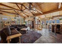 Spacious living room featuring wood-beam ceilings, skylights, tile flooring, and a comfortable leather sofa at 829 Colorado Blvd, Idaho Springs, CO 80452