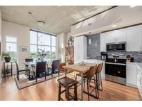 Open-concept living space featuring modern kitchen, dining area, and large windows showcasing city views at 1700 Bassett St # 513, Denver, CO 80202