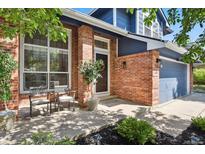 Inviting front porch with brick facade, chairs and an elegant front door in a charming curb appeal setting at 10291 Carrara Ter, Parker, CO 80134