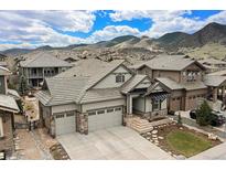 Stunning home featuring a three-car garage and stone accents, set against a scenic mountain backdrop at 15784 Burrowing Owl Ct, Morrison, CO 80465