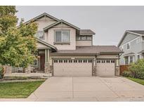 Charming two-story home featuring a three-car garage and welcoming front porch with stone accents at 8317 Liverpool Cir, Littleton, CO 80125
