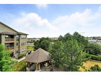 View from the condo balcony of the community gazebo, green space and treeline under a cloudy blue sky at 8489 Canyon Rim Cir # 302, Englewood, CO 80112