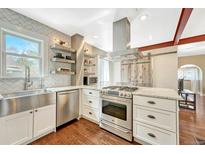 Modern kitchen with stainless steel appliances, floating shelves, white cabinets, and an island with a marble countertop at 4720 W 39Th Ave, Denver, CO 80212