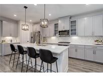 Modern kitchen features gray cabinets, stainless steel appliances, a central island with seating and pendant lighting at 431 Courtfield Way, Castle Pines, CO 80108