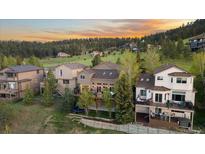 A well-kept home with a spacious deck overlooks a grassy, wooded lot at sunset at 24005 High Meadow Dr, Golden, CO 80401