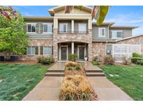 Inviting townhouse with a stone facade, lush landscaping, and a well-maintained front yard at 11364 Xavier Dr # 205, Westminster, CO 80031