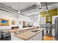 Open kitchen with breakfast bar and stainless steel appliances, and an industrial-style ceiling and pendant lighting at 1435 Wazee St # 504, Denver, CO 80202