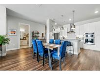 Bright dining room features a wooden table with blue velvet chairs and modern pendant lighting at 20 Wilcox St # 208, Castle Rock, CO 80104