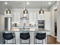Modern kitchen featuring stainless steel appliances, white cabinetry, island with seating and stylish pendant lighting at 20 Wilcox St # 208, Castle Rock, CO 80104