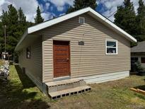 Charming one-story home with light tan siding and a wooded surrounding landscape at 325 Aspen Rd, Idaho Springs, CO 80452