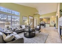 Bright living room with large windows, tile floors, and an open floor plan leading to dining and kitchen areas at 9742 E Hawaii Pl, Aurora, CO 80247