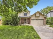 Charming two-story home featuring a well-manicured lawn, mature trees, and a two-car garage at 3210 S Espana Cir, Aurora, CO 80013