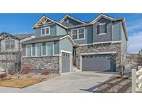 Charming two-story home featuring a combination of stone veneer and blue siding, with a gray two car garage at 27185 E Costilla Dr, Aurora, CO 80016