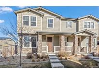 Inviting townhouse with stone accents, covered porch, and landscaped front yard at 13734 Ash Cir, Brighton, CO 80602