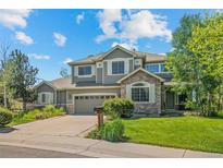 Inviting two-story home featuring a stone facade, lush lawn, and mature trees at 15904 W 58Th Ave, Golden, CO 80403