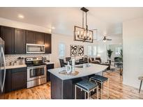 Modern kitchen featuring stainless steel appliances, an island with seating, and stylish light fixtures at 2426 S Acoma St, Denver, CO 80223