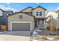 Two-story home with stone and siding exterior, gray garage door, and small front porch at 13372 E 110Th Way, Commerce City, CO 80022