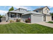 Charming gray home featuring an attached garage and a well-maintained lawn at 8761 Cloverleaf Cir, Parker, CO 80134