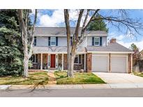 Charming two-story home featuring a brick facade, manicured lawn, and a welcoming red front door at 6964 S Olive Way, Centennial, CO 80112