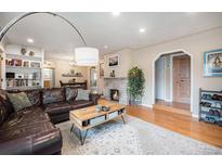 Inviting living room featuring a stone fireplace, hardwood floors, and a comfortable leather sofa at 895 Vance St, Lakewood, CO 80214