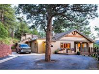 Inviting front exterior with a charming porch and natural landscaping with a big tree at 150 Hess Ave, Golden, CO 80401