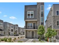 Modern gray three-story home with stone accents and a small balcony at 20999 E Quincy Dr, Aurora, CO 80015