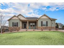Charming single-story home with a covered porch, manicured lawn, and stone accents at 23440 E Rockinghorse Pkwy, Aurora, CO 80016