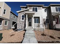 Modern two-story townhome with stone accents, a covered porch, and a well-maintained front yard at 6628 N Nepal Ct, Aurora, CO 80019