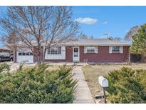 Charming brick ranch home featuring mature landscaping, attached garage, and easy access front entry at 6185 Sheridan Blvd, Arvada, CO 80003