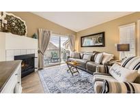 Cozy living room featuring a fireplace, plush seating, and sliding glass doors to the balcony at 8334 Pebble Creek Way # 201, Highlands Ranch, CO 80126