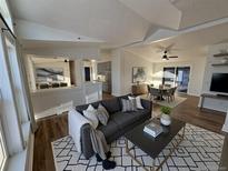 Open-concept living room featuring a modern fireplace, vaulted ceilings, and lots of natural light at 7070 Henry St, Fort Lupton, CO 80621